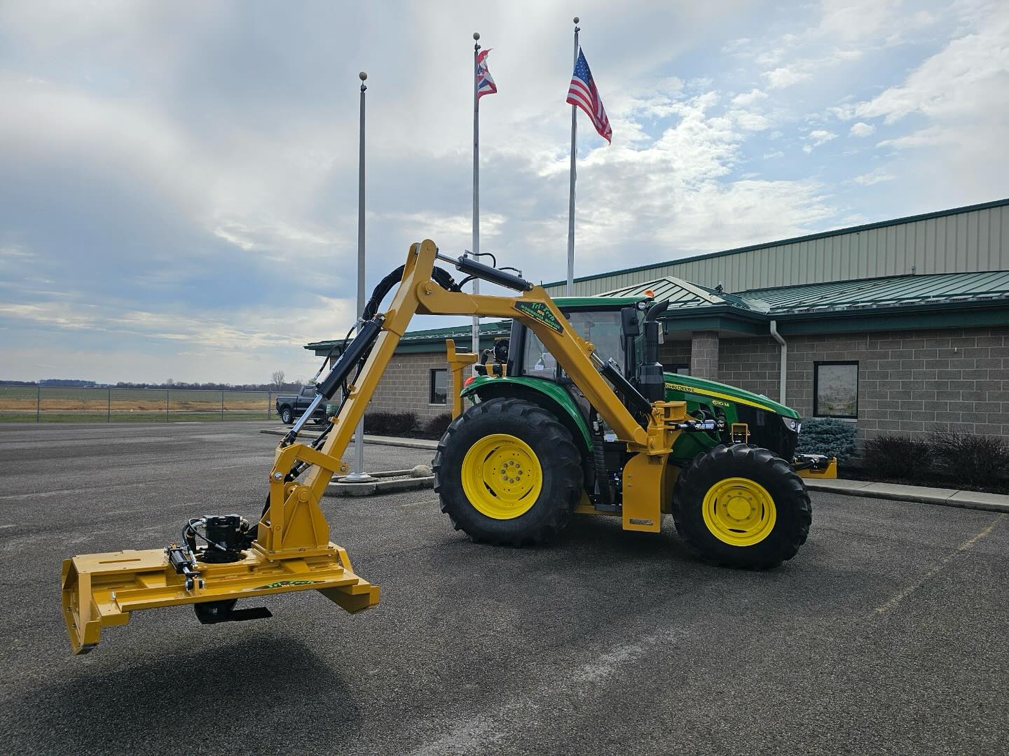 Boom-mounted rotary mower on tractor
